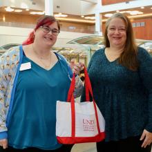 Two people holding a white and red canvas bag