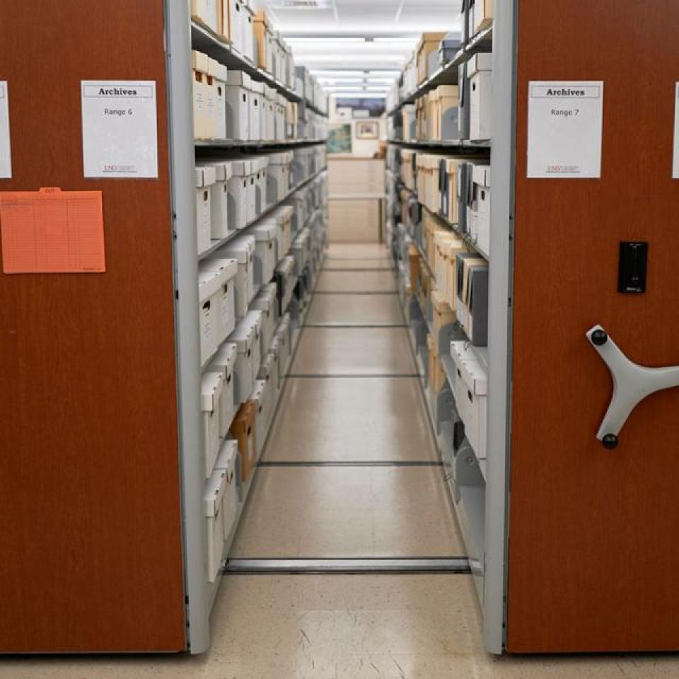 Compact shelving in an archive with labeled panels and storage boxes.