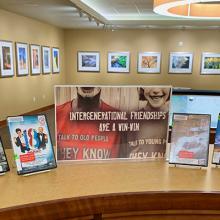 Image of DVD cases next to a sign that reads Intergenerational Friendships Are A Win-Win.