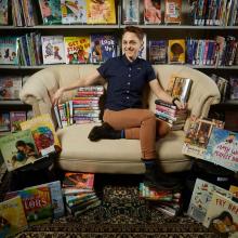 Amanda Melilli sitting on a chair surrounded by diverse books