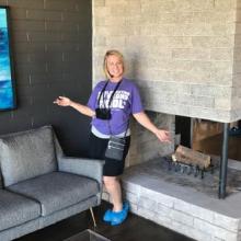 Amy Rayner standing in front of a fireplace giving a tour of a mid-century modern house in Las Vegas.