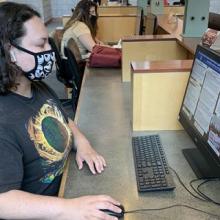 Student sitting at computer desk in library for remote class