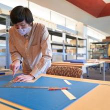 Archival processing assistant Jimmy Chang cuts acid-free boards to create a custom storage solution for metal advertising proofs