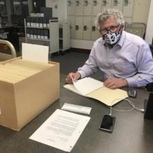 2021 Eadington Fellow, Dr. Fred Woods sitting at desk with archival files