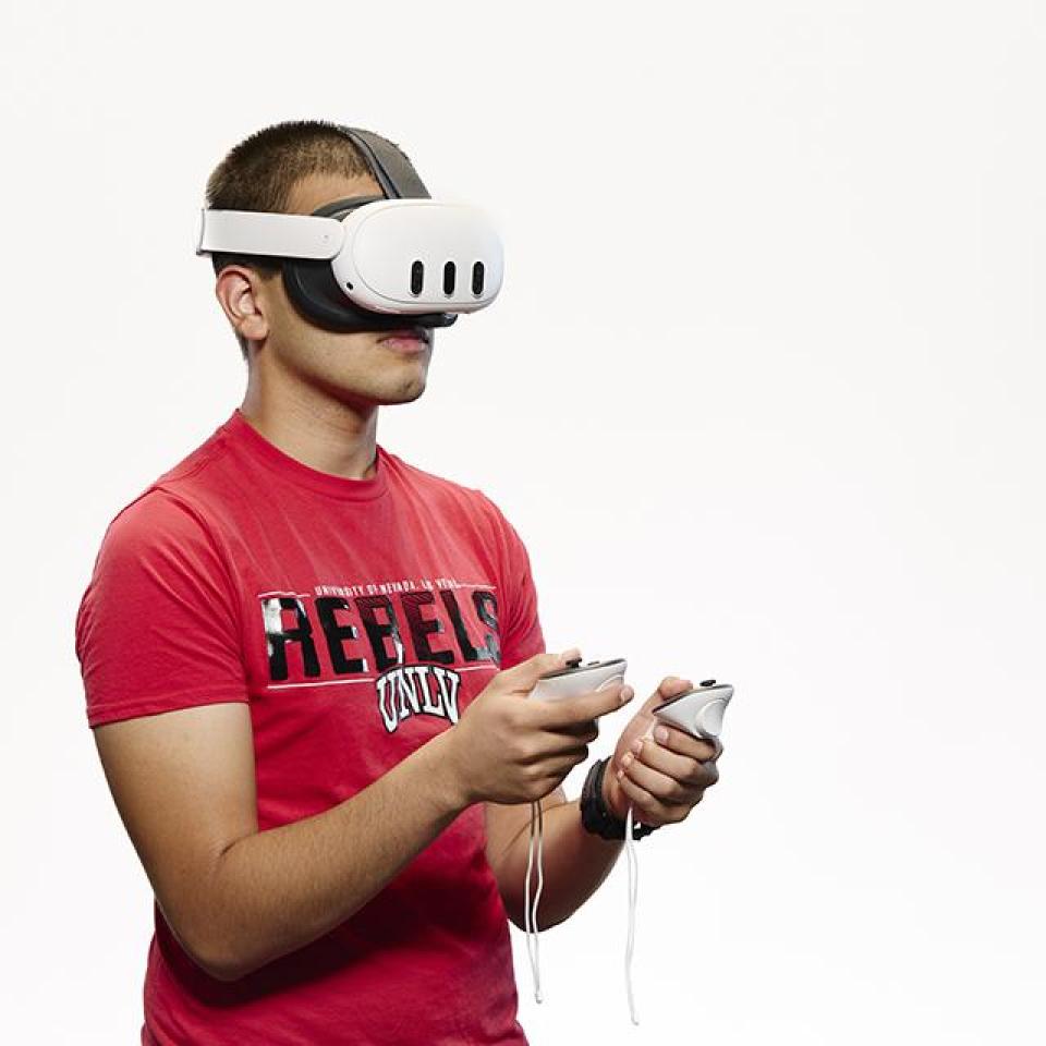UNLV student wearing a VR headset and holding controllers.
