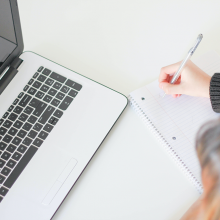 Student at desk with notepad and laptop